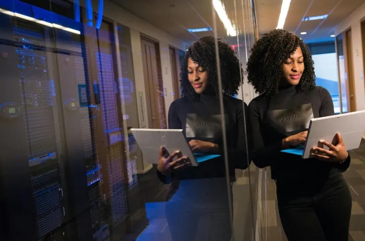 Two data center staff reviewing tablets in a server aisle